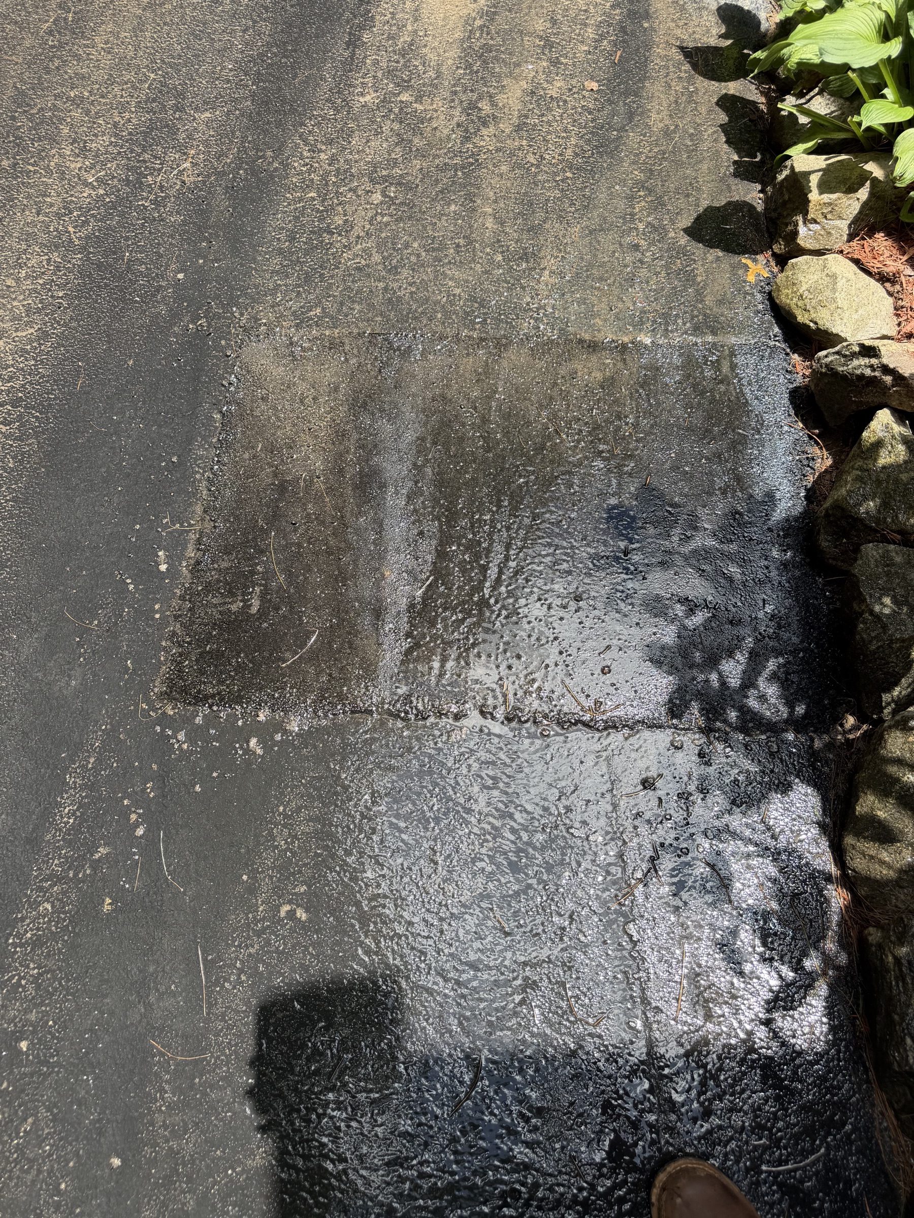 Localized asphalt patch at a stone planting edge